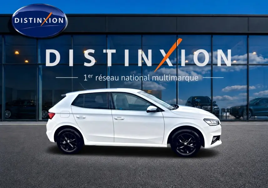 Vue de profil côté gauche d'une Skoda Fabia blanche 2025 avec jantes noires devant une vitrine Distinxion.