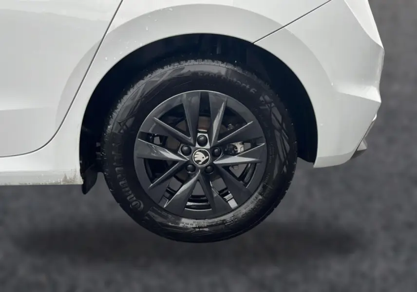 Gros plan sur la roue arrière droite d'une Skoda Fabia blanche avec jante alliage gris foncé et logo central.