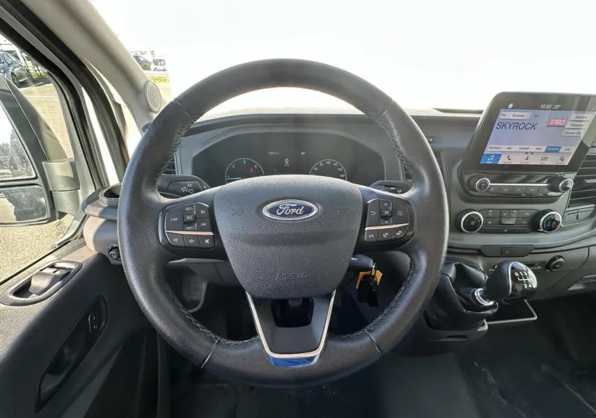 Vue intérieure centrée sur le volant cuir Ford et la console centrale avec écran tactile du Ford Transit Fourgon blanc 2020.