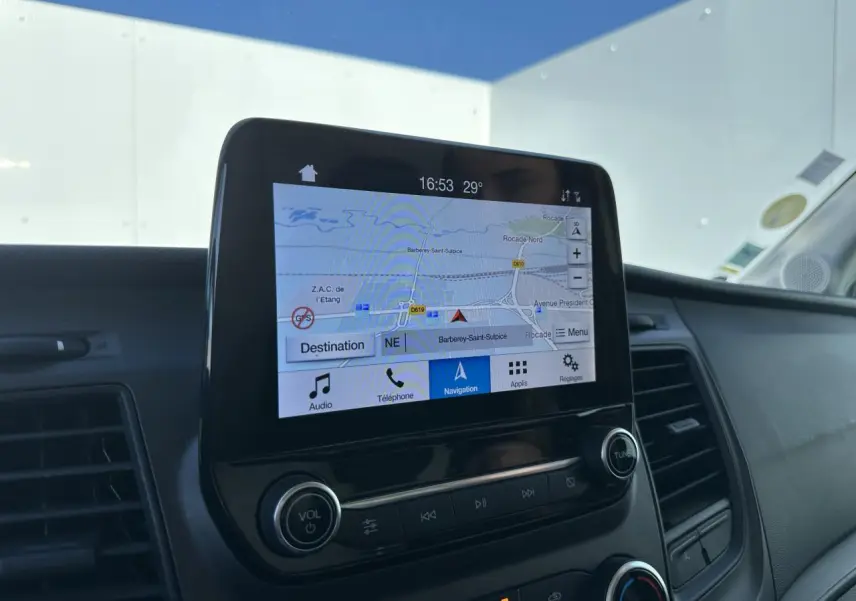Écran tactile central du Ford Transit Fourgon blanc 2020 affichant la navigation GPS, entouré de commandes audio et climatisation.