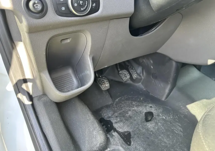 Vue rapprochée côté conducteur du pédalier et du rangement sous tableau de bord du Ford Transit Fourgon blanc 2020.