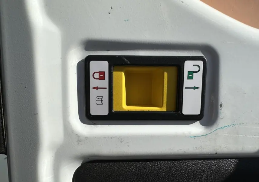 Poignée de porte intérieure jaune avec indicateurs de verrouillage sur panneau blanc du fourgon Ford Transit blanc.