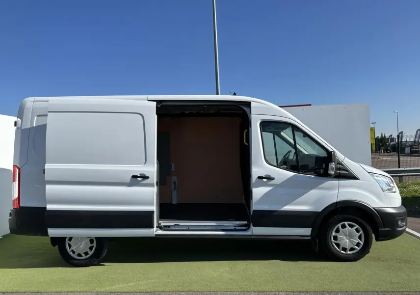 Vue latérale droite d'un Ford Transit Fourgon blanc avec porte coulissante ouverte montrant l'espace de chargement vide.