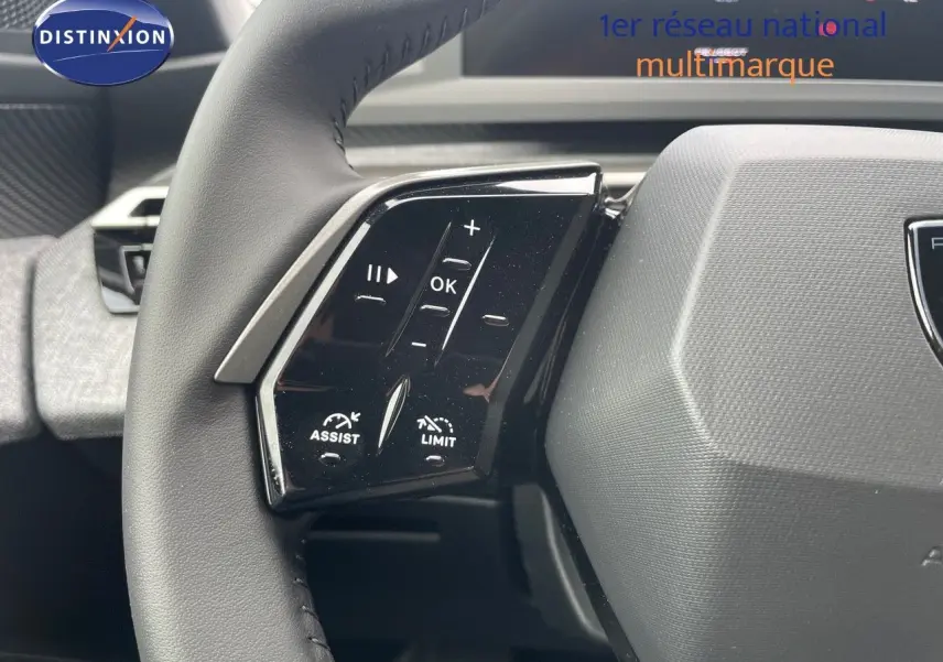 Gros plan sur la partie gauche du volant noir du Peugeot 3008 Hybrid 2025 avec commandes intégrées et logo Peugeot visible.