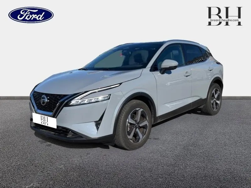 Nissan Qashqai 1.3 Mild Hybrid gris Argile en 3/4 avant droit, avec jantes alu et phares LED distinctifs.