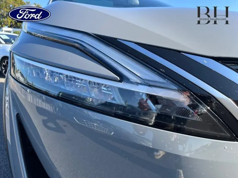 Gros plan sur le phare avant droit du Nissan Qashqai 1.3 Mild Hybrid gris Argile, soulignant ses lignes modernes.