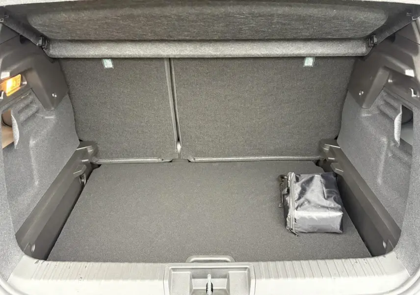 Coffre ouvert vu de face d’un Renault Captur blanc nacré, avec un sac noir posé à droite.