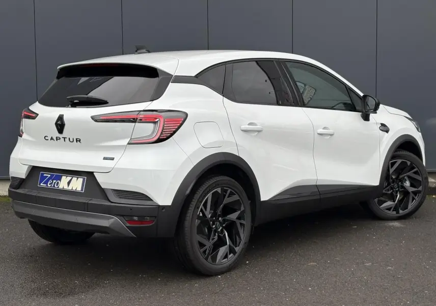 Vue 3/4 arrière droite d'un Renault Captur blanc nacré avec jantes noires et vitres surteintées.