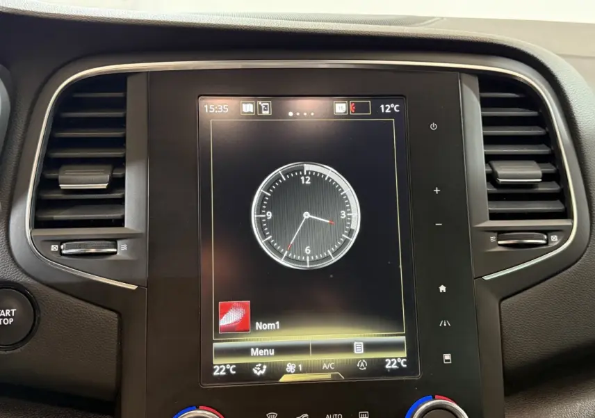 Écran tactile central affichant une horloge digitale dans le tableau de bord d'une Renault Mégane gris foncé, vue de face.