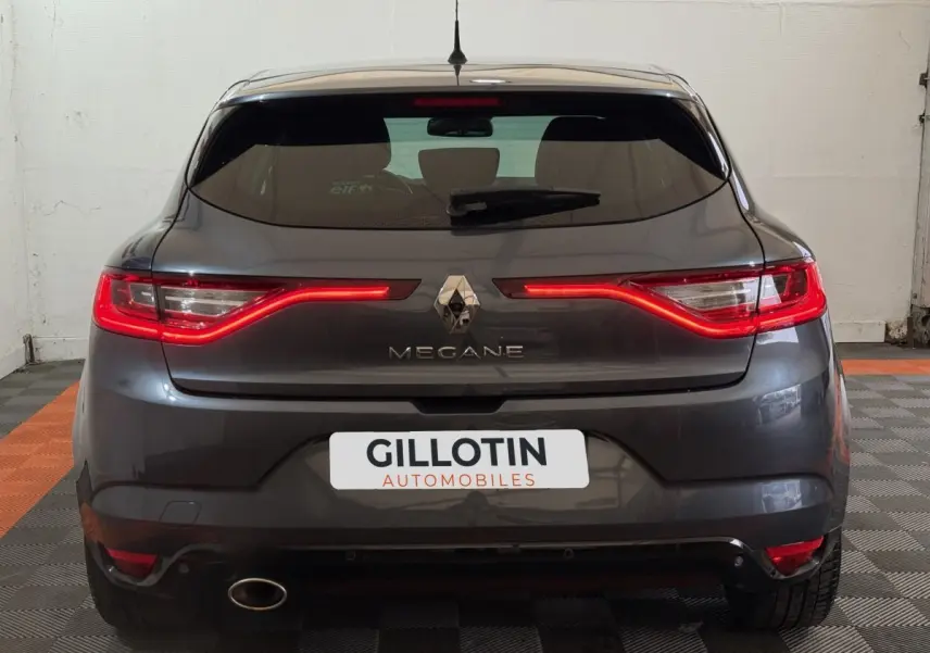 Vue arrière d'une Renault Mégane gris foncé avec feux LED allumés dans un garage.