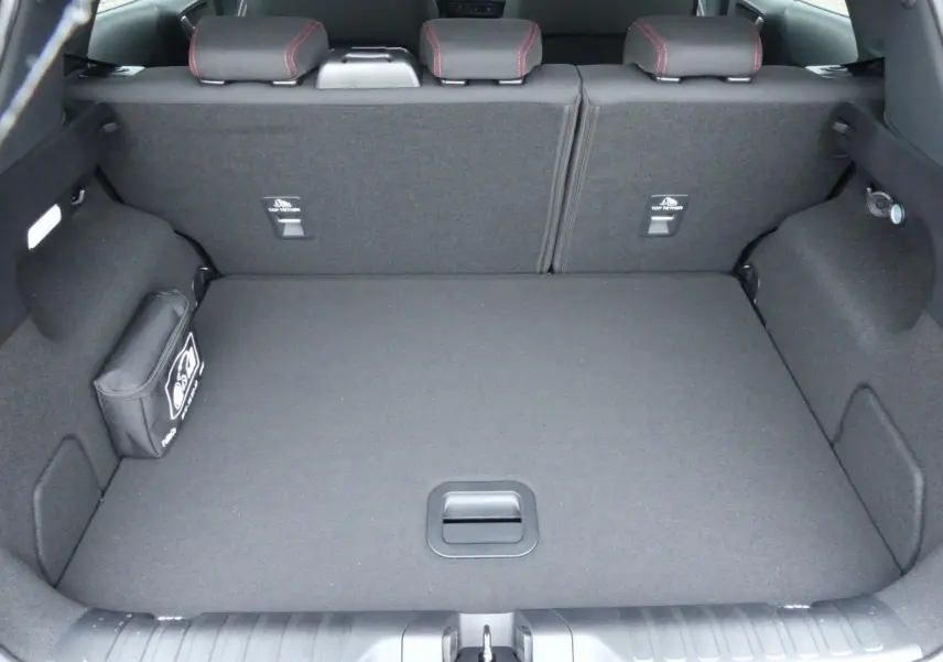 Vue du coffre spacieux et tapis noir du Ford Puma 2025 gris métallisé, avec sièges arrière rabattus et trousse de secours.