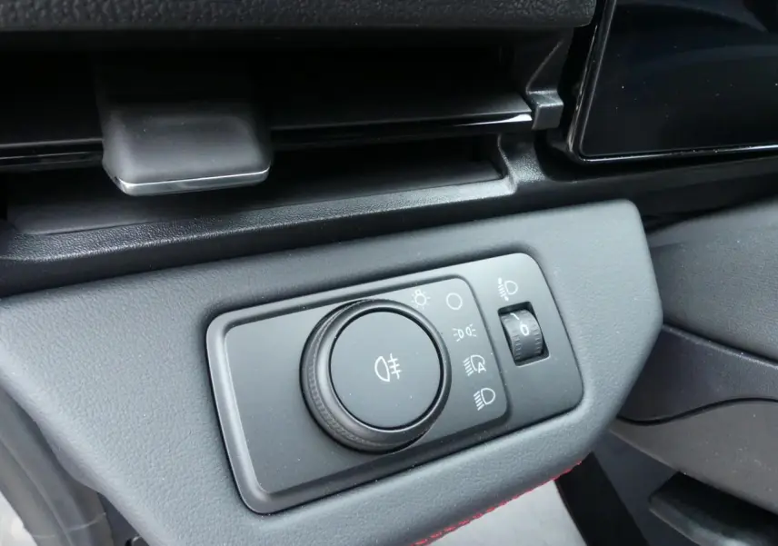 Gros plan sur le bouton de réglage des phares dans l'habitacle du Ford Puma 2025 gris métallisé.