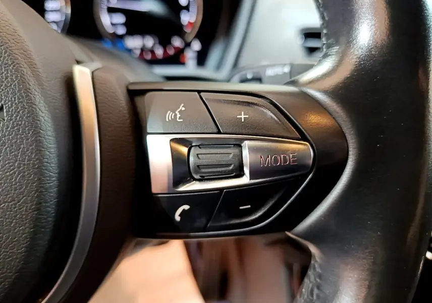 Gros plan sur les commandes multifonctions du volant noir d’une BMW X2 sDrive20i M Sport 2019.