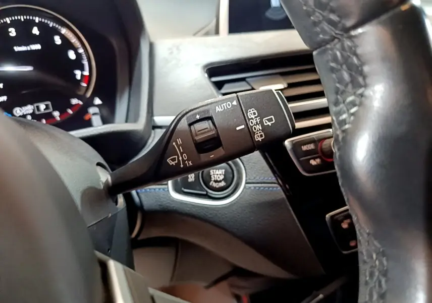 Gros plan sur la manette d’essuie-glace et le bouton start/stop du tableau de bord d’une BMW X2 bleu 2019.