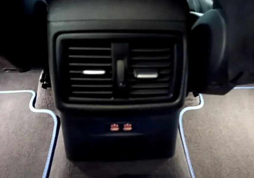 Vue rapprochée des bouches d’aération arrière noires et des ports USB sur la console centrale d’un BMW X2 bleu.
