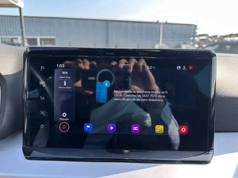 Écran tactile central du tableau de bord du SEAT Arona 2025, affichant le menu Bluetooth avec reflet extérieur.