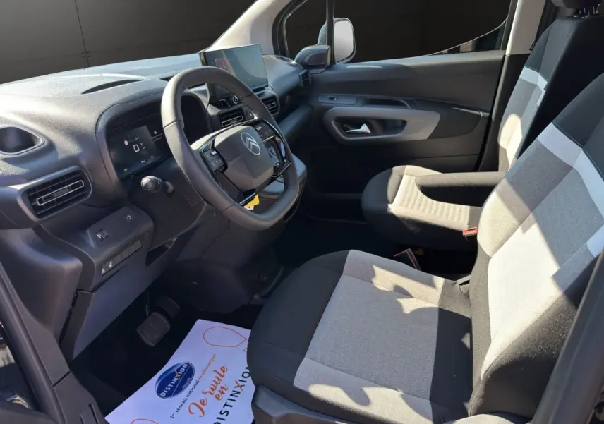 Vue intérieure côté conducteur du Citroën Berlingo noir 2026, avec tableau de bord moderne et sièges tissu bicolore.
