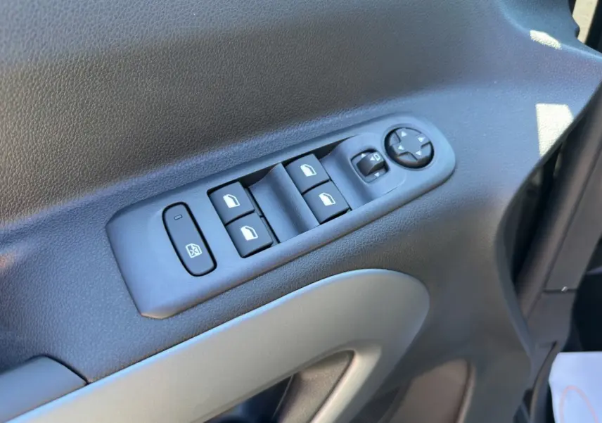 Gros plan sur les commandes des vitres électriques et rétroviseurs sur la portière côté gauche du Citroën Berlingo noir 2026.