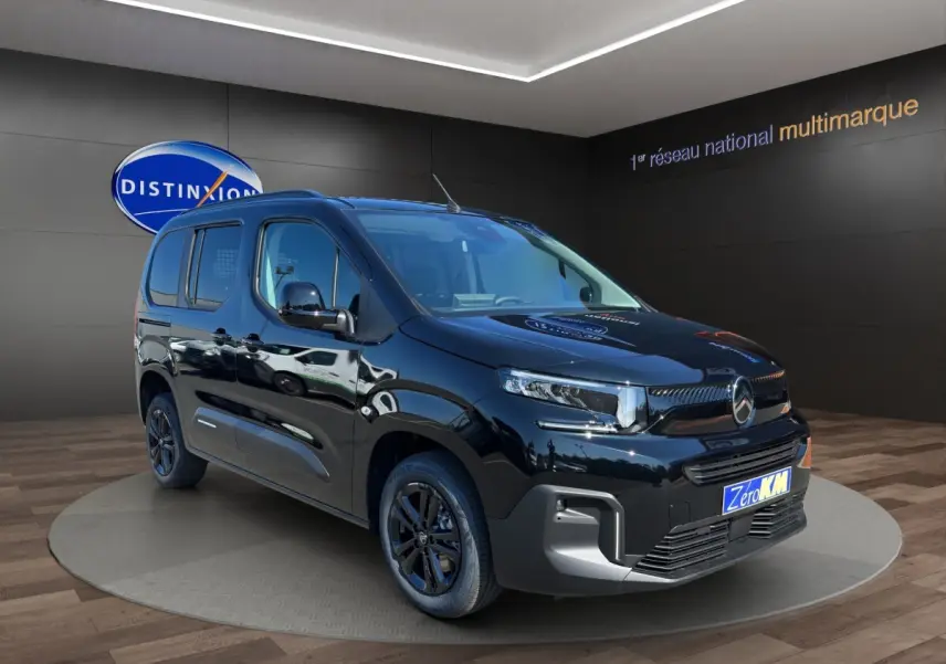 Vue 3/4 avant gauche du Citroën Berlingo noir 2026 avec jantes noires, présenté en showroom intérieur.