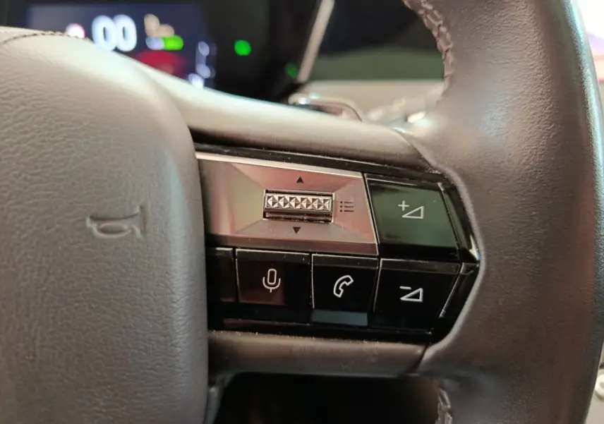 Gros plan sur les commandes à droite du volant cuir noir du DS4 E-TENSE 225 gris clair, avec boutons de volume et appel.