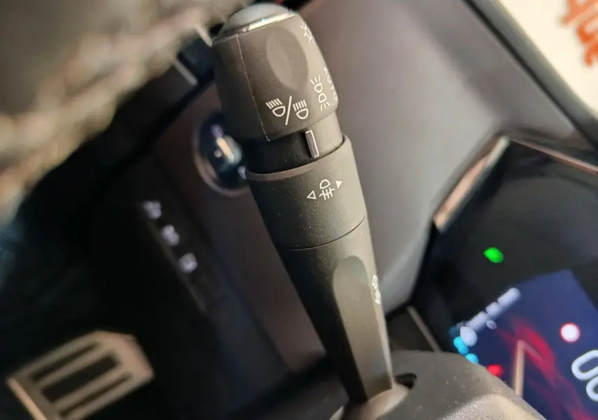 Gros plan sur la commande des feux au volant d’une DS4 E-TENSE 225 gris clair, intérieur noir.