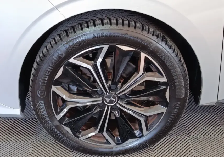 Gros plan sur la roue avant droite d’une DS4 E-TENSE 225 gris clair avec jante alliage noire et argentée.