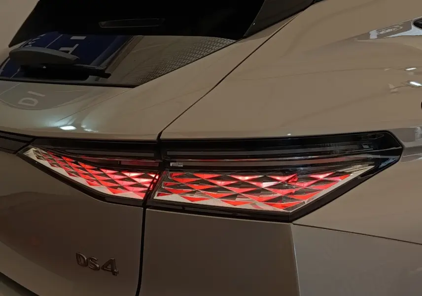Gros plan sur le feu arrière droit rouge et blanc d’une DS4 E-TENSE 225 gris clair, vue arrière côté droit.