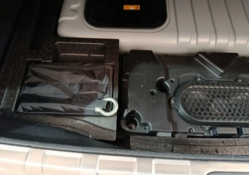 Détail du rangement sous le plancher du coffre du DS4 E-TENSE 225 gris clair, montrant un kit de secours et compartiments.