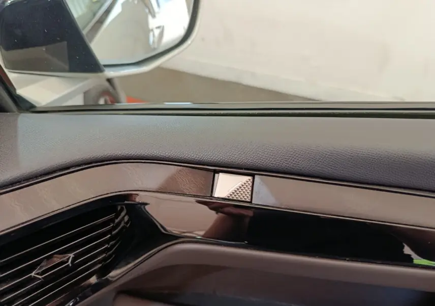 Détail intérieur de la portière côté gauche d'une DS4 E-TENSE 225 gris clair, avec insert noir brillant et bouton triangulaire.
