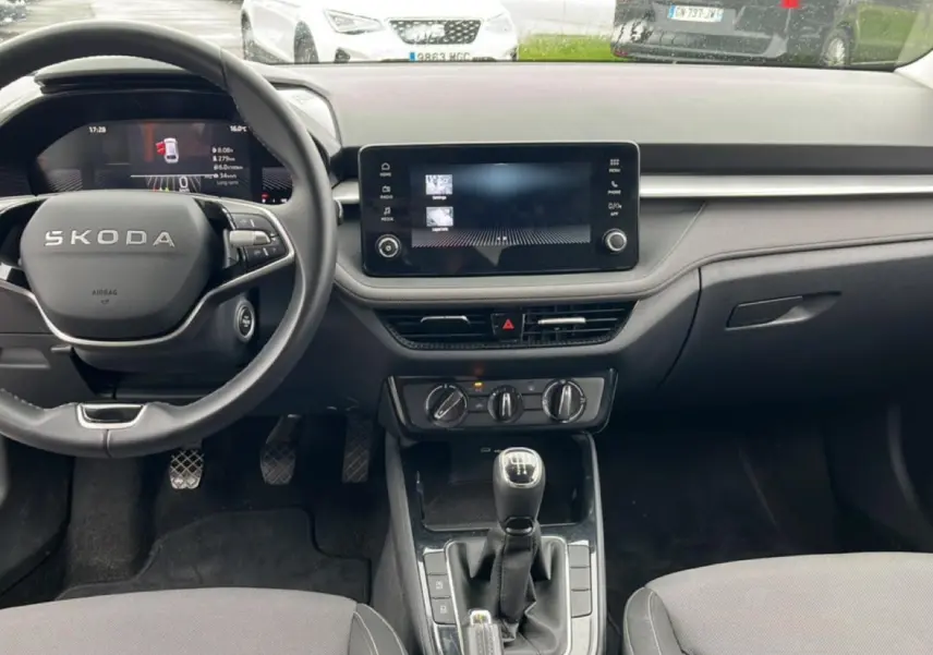 Vue intérieure avant de la Skoda Fabia blanche 2025, volant cuir multifonction et écran tactile central visible.