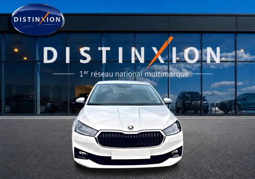 Vue frontale d'une Skoda Fabia blanche 2025 garée devant une vitrine avec logo Distinxion.