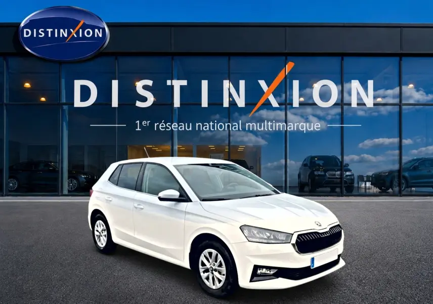 Vue 3/4 avant droite d'une Skoda Fabia blanche stationnée devant une vitrine avec logo Distinxion.