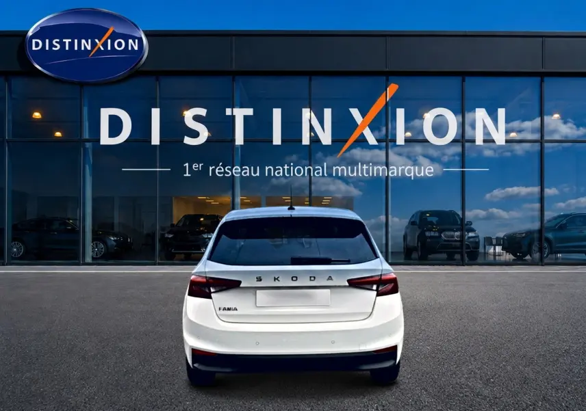 Vue arrière d'une Skoda Fabia blanche 2025 garée devant une vitrine avec logo Distinxion.