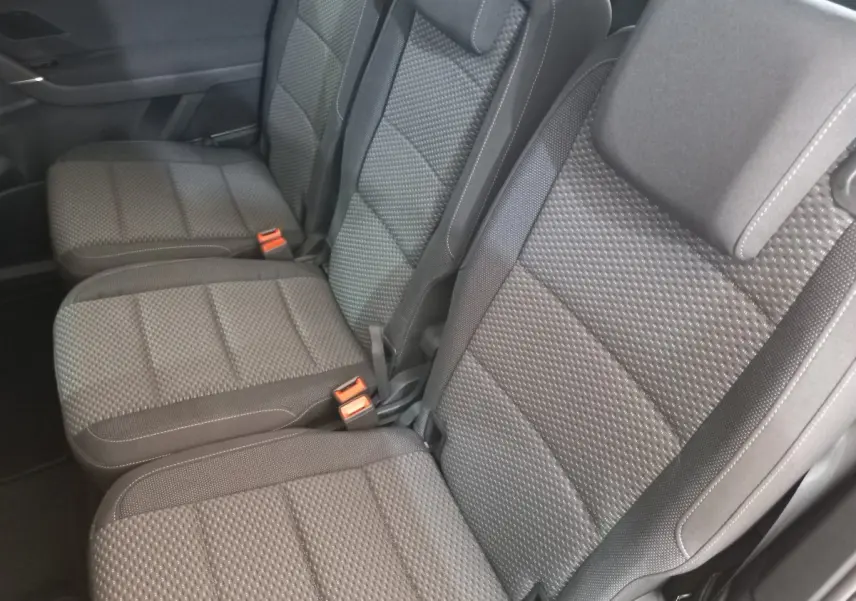 Vue rapprochée des sièges arrière gris texturés du Volkswagen Touran 2024, version 7 places, avec ceintures et boucles visibles.