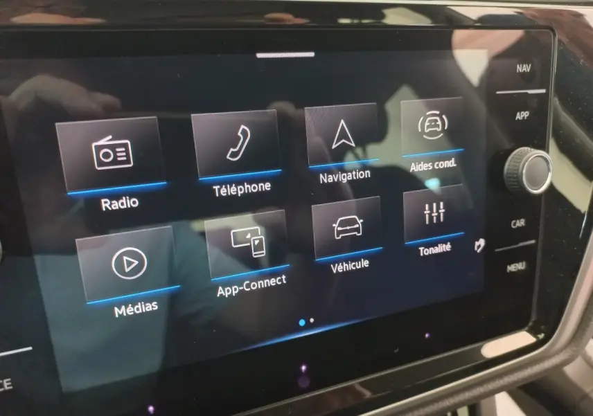 Écran tactile central du Volkswagen Touran 2024 affichant les options radio, téléphone, navigation et aides à la conduite.
