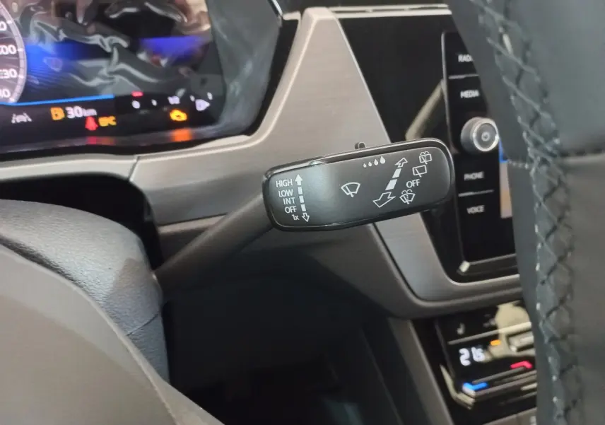 Gros plan sur la commande d’essuie-glace à gauche du volant dans l’habitacle noir du Volkswagen Touran 2024.