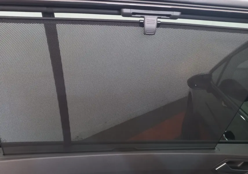 Vue intérieure côté droit du pare-soleil en filet du Volkswagen Touran noir 2024, volet déployé sur la vitre arrière.