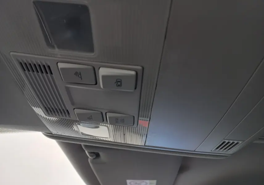 Vue intérieure en gros plan du plafonnier gris avec commandes d’éclairage et verrouillage du Volkswagen Touran 2024 noir.