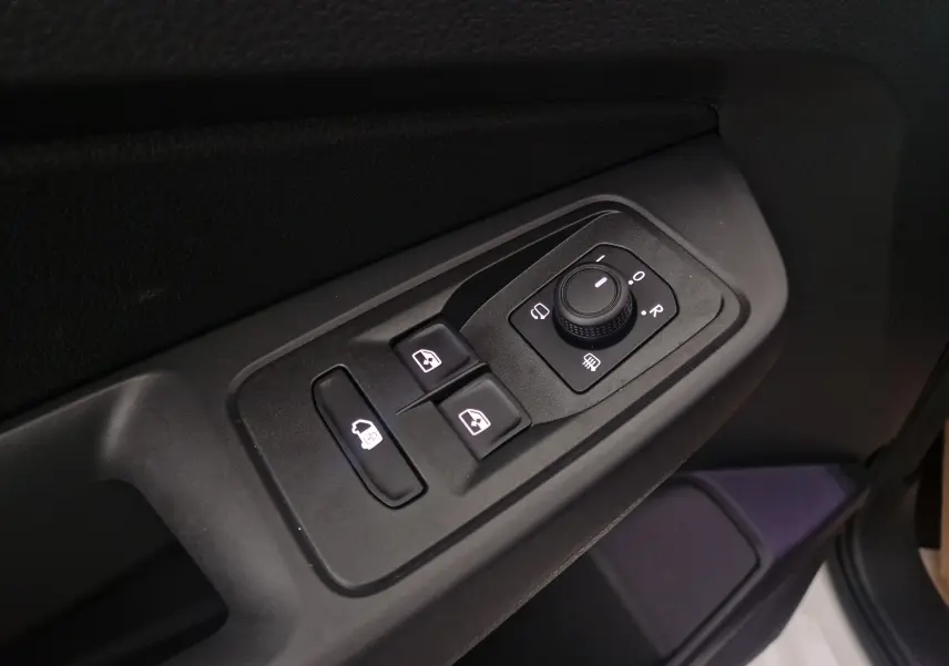 Gros plan sur les commandes des vitres et rétroviseurs côté conducteur du Volkswagen Caddy Maxi blanc 2025.