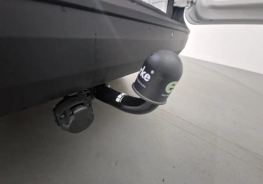 Gros plan sur l'attelage noir avec cache protecteur du Volkswagen Caddy Maxi blanc, vu par l'arrière droit.