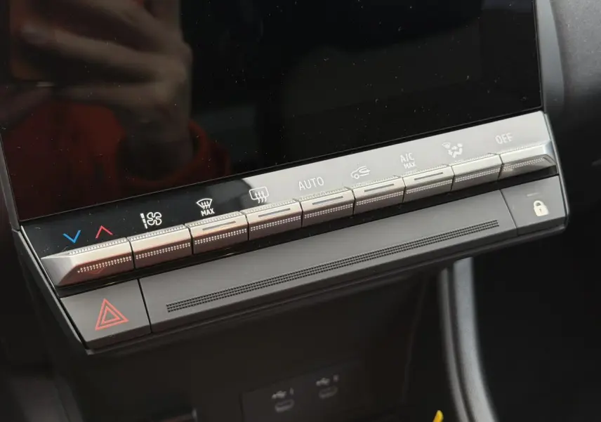 Gros plan sur la console centrale du Renault Captur 2025, boutons de climatisation et écran tactile noir éteint.