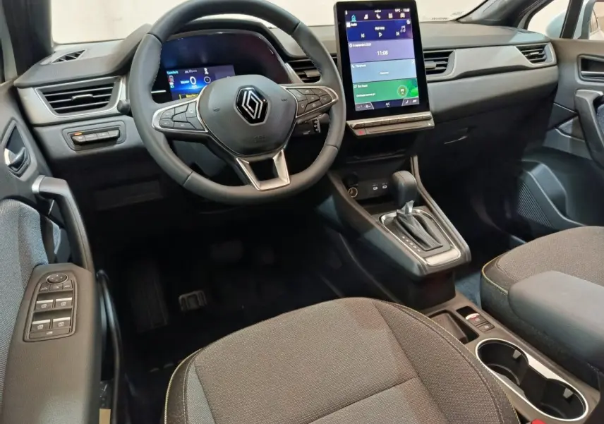 Vue intérieure avant du Renault Captur blanc 2025, volant multifonctions, écran tactile vertical et console centrale avec boîte auto.