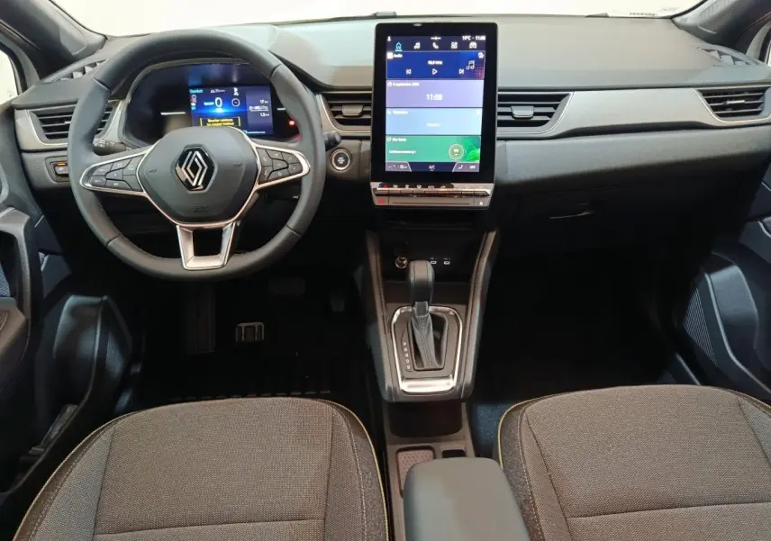 Vue intérieure avant du Renault Captur 2025, tableau de bord avec écran tactile vertical et volant multifonctions en cuir.