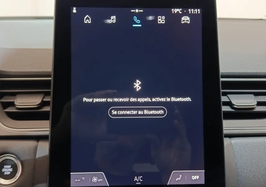 Écran tactile central allumé du tableau de bord du Renault Captur blanc, avec bouton démarrage visible à gauche.