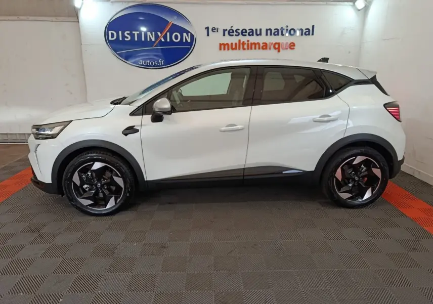 Profil latéral gauche d'un Renault Captur blanc 2025 en version techno E-Tech full hybrid, roues noires à jantes stylisées.