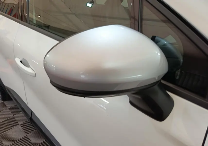 Rétroviseur côté gauche blanc du Renault Captur 2025 techno E-Tech full hybrid, avec porte et vitre partiellement visibles.