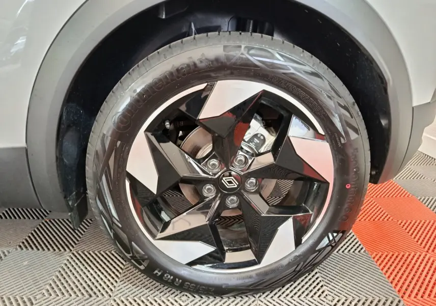 Gros plan sur la roue avant droite du Renault Captur blanc 2025 avec jante noire et argentée au design géométrique.