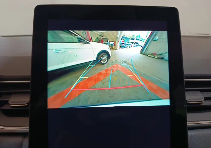 Affichage caméra de recul montrant un Renault Captur blanc en 3/4 arrière droit avec lignes de guidage colorées.