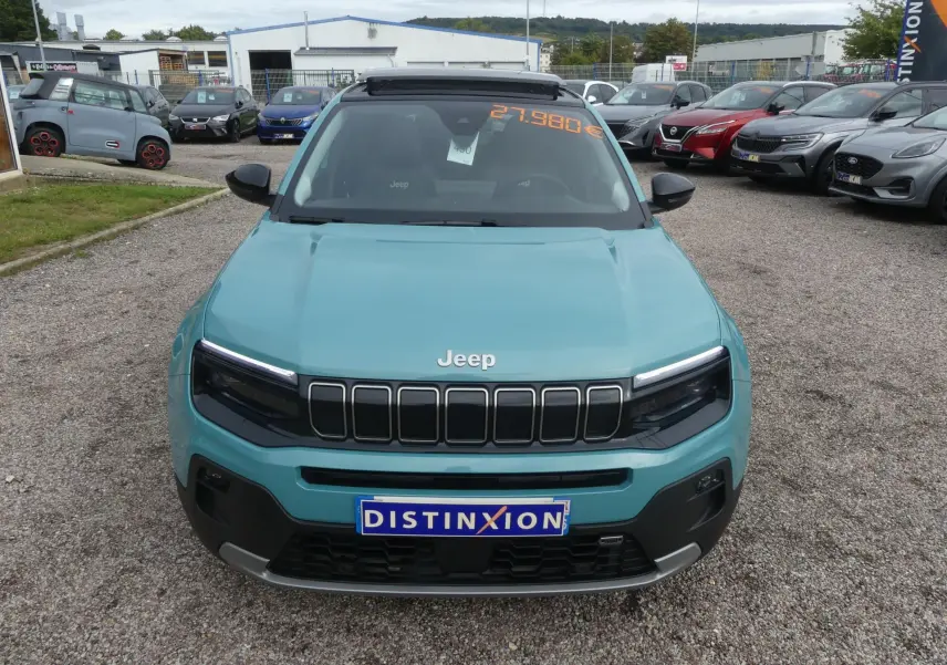 Vue avant d'un Jeep Avenger bleu métallisé 2024 avec calandre noire et plaque Distinxion sur parking.