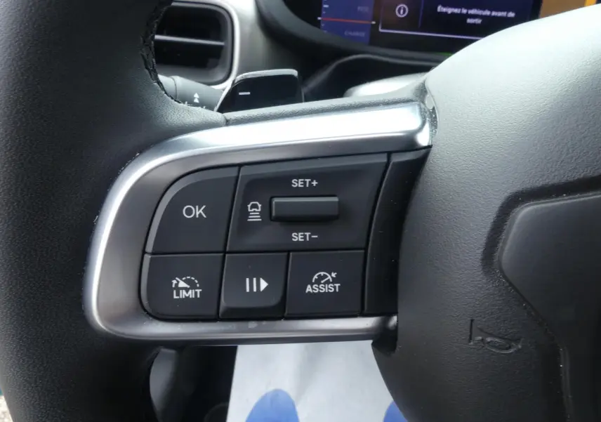 Gros plan sur les commandes au volant gauche du Jeep Avenger 2024, finition Summit, avec boutons de régulateur et assistance.